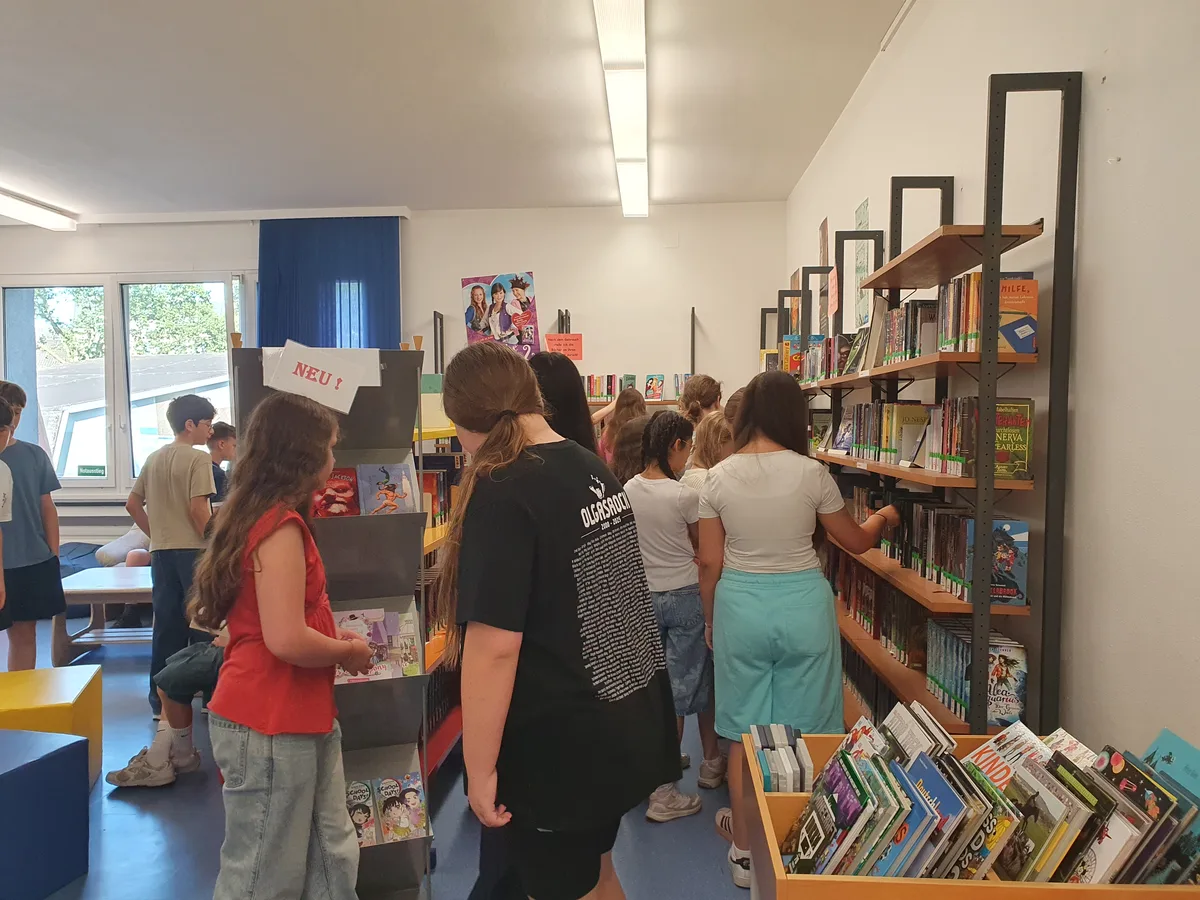 Schüler:innen stöbern an den Bücherregalen der Schulbücherei